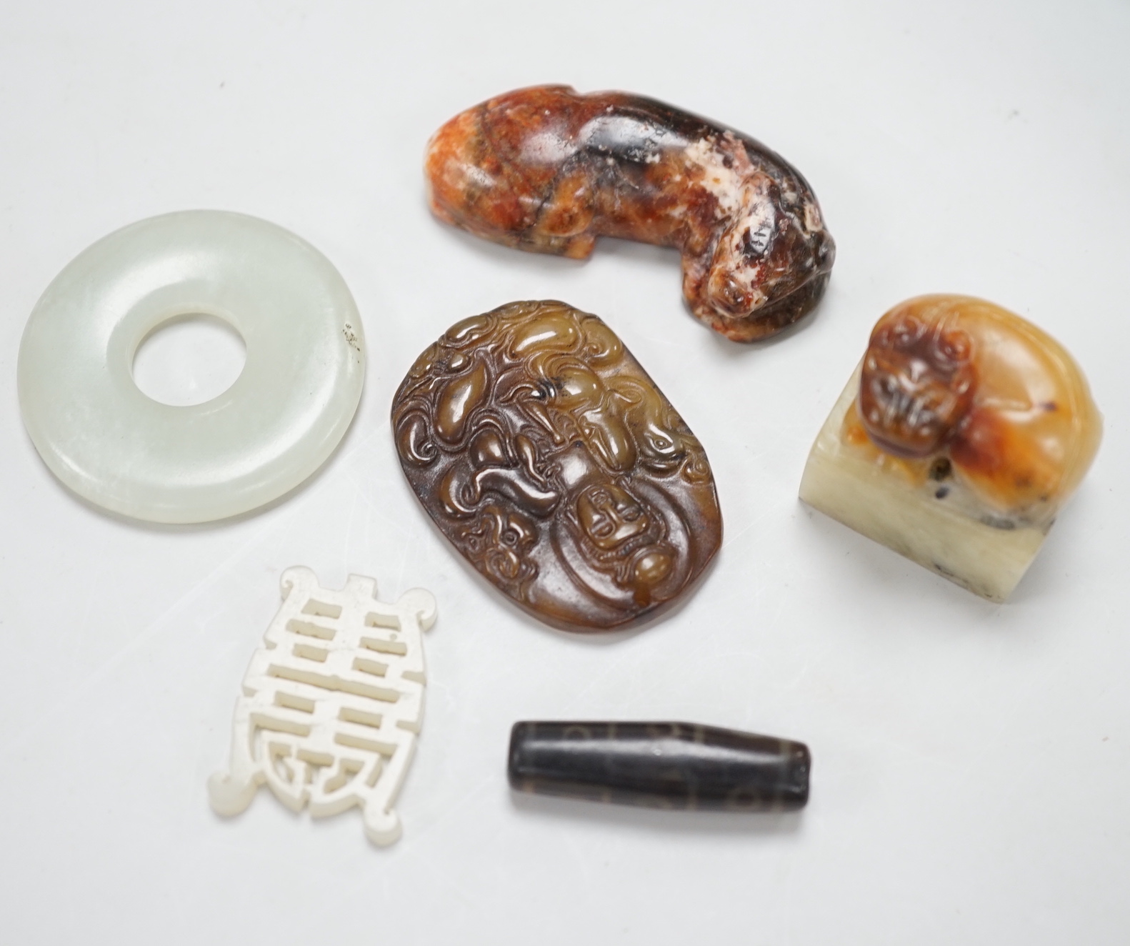 A Chinese pale celadon jade bi disc, a jade carving of the character ‘Shou’ , two hardstone carvings of creatures, an agate pendant of Guanyin in Tang dynasty style and a stained glass , bead in Tibetan style (6), disc 4
